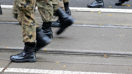 Generic army soldiers marching through the street in green camo uniforms and black boots, copy space background, group of people, news shot Motion, movement infantry training parade operations concept