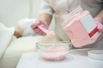Beautician prepare of a moisturizing mask from powder for her female client at spa.