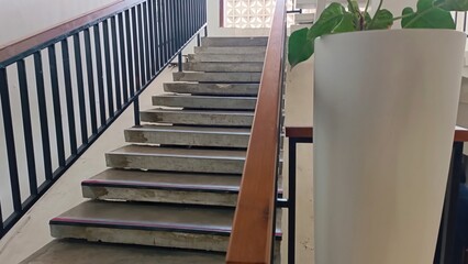 A staircase with a plant in a white vase