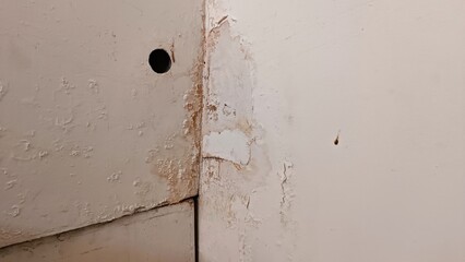 A wall with a hole in it and a white paint on it