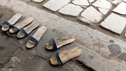 A row of old wooden slippers are on the sidewalk