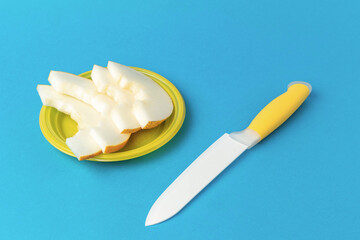 Sliced Melon on Yellow Plate with White Knife on Vibrant Blue Background