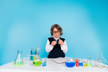 Photo of smart clever diligent charming boy wear uniform learning chemistry lab subject isolated on blue color background