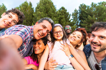 Happy multiracial friends taking selfie pic with smart mobile phone in park – diverse young people taking selfie portrait – multiethnic having fun outside – group young people smiling at camera outdoo