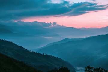 Fototapeta premium Mountain valley bathed in soft pink and blue hues at dawn with misty clouds