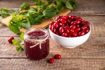 Cornelian cherry, dogwoods edible berry jam or marmalade in small jar with fresh berries on kitchen table, copy space