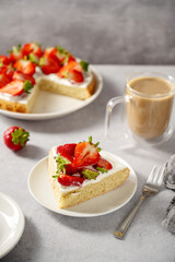 Slice of sponge cake with fresh strawberries, served with cup of coffee