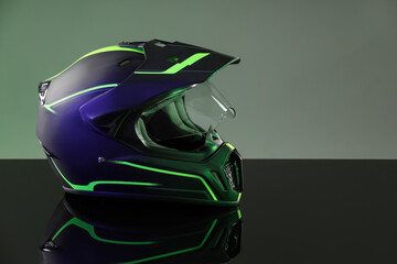 Modern motorcycle helmet with visor on mirror surface against grey background. Space for text