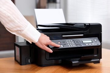 Woman using modern printer at workplace indoors, closeup