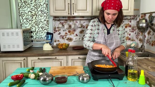 Culinary concept, preparation ingredients for homemade food. A young adult beautiful woman in an apron cooking a meal, makes mirepoix on a kitchen counter indoors. Home cooking and gastronomy passion