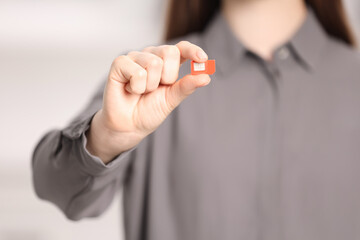 Woman holding modern SIM card indoors, closeup