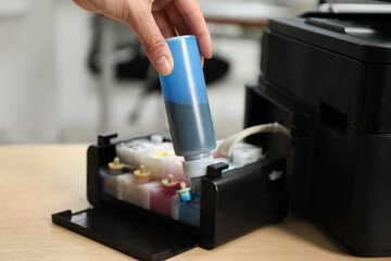 Woman refilling ink in modern printer at workplace indoors, closeup