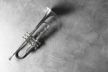 Shiny trumpet on grey textured table, top view. Space for text. Wind musical instrument