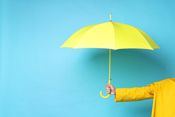 Man holding yellow umbrella on light blue background, space for text