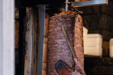 Rotating spit with meat being sliced for shawarma. Juicy and flavorful cuts