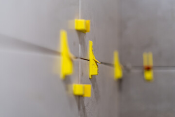 Plastic clips and wedges securing tiles in place for perfect alignment.