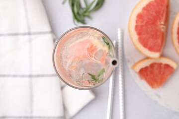 Refreshing water with grapefruit and rosemary in glass on light table, flat lay