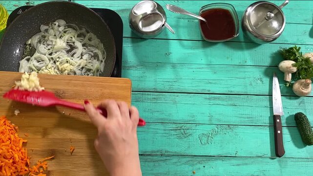 Culinary concept, preparation ingredients for homemade food. A young adult beautiful woman in an apron cooking a meal, makes mirepoix on a kitchen counter indoors. Home cooking and gastronomy passion