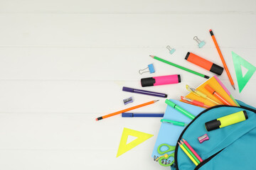 Backpack and different school supplies on white wooden background, flat lay. Space for text
