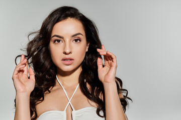 Appealing woman with long hair posing on white backdrop.