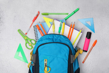 Flat lay composition with backpack and different school stationery on light grey table