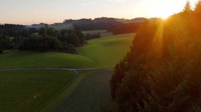 Bavarian foothills of the Alps in southern Germany at sunset, forest and green pastures