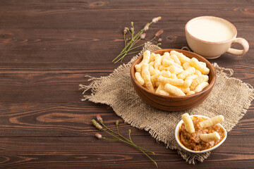 Corn flakes sticks with caramel in wooden bowl on brown wooden, Side view, copy space.