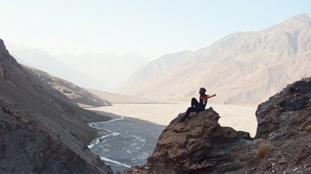 Caucasian hiker fit traveler stand on hilly viewpoint in Pamir mountains wild bartang valley enjoy landscape.Traveling on hill peaks landscape. Sport, tourism and hiking concept. Watching sunrise
