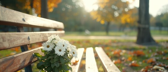  A tight shot of a weathered bench with a flower pot positioned on one side Behind it, a tree stands tall in the backdrop