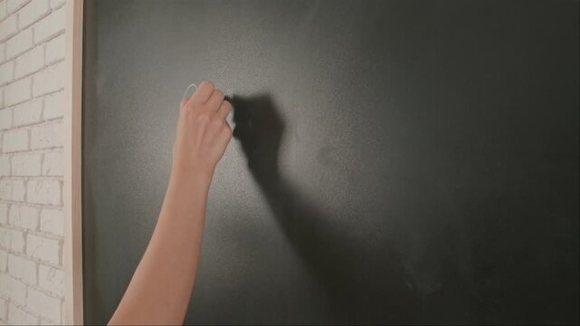 Close up of woman hand writing chemistry formulas on chalkboard, professor writes on blackboard or student solving task. Education and science concept.