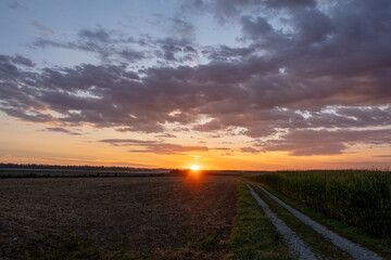 Golden late summer sunrise over a harvested grain field with footpath, Bavaria, travel Germany 
