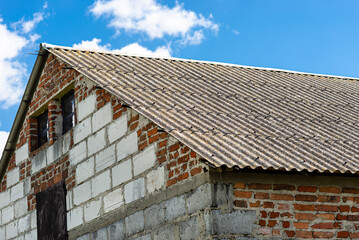 An old brick barn in the Polish countryside with a corrugated asbestos roof.