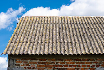 An old brick barn in the Polish countryside with a corrugated asbestos roof.