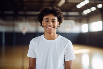 Fototapeta premium Portrait of a smiling male African American teenager in basketball gym