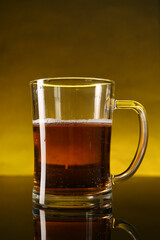 Glass of beer with froth on dark table, closeup
