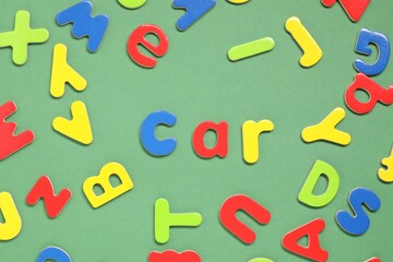 Word Car made of magnetic letters on green background, flat lay. Learning alphabet