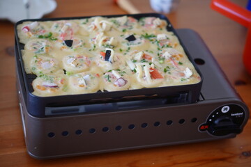 たこ焼き器に具材を入れてたこ焼きを焼くところ