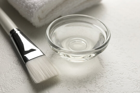 Peeling procedure. Chemical peel liquid in bowl, towel and brush on white table, closeup