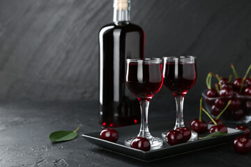 Delicious cherry liqueur and berries on black table