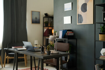 Home office setup with modern furnishings featuring sleek desk, organized bookshelves, and artistic wall decor on dark accent wall creating a serene workspace ambiance