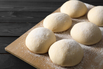 Raw dough balls on black wooden table