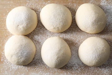 Raw dough balls on wooden table, top view