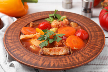 Tasty homemade stew with vegetables on white wooden table, closeup