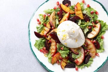 Plate with fresh burrata salad on grey textured table, top view