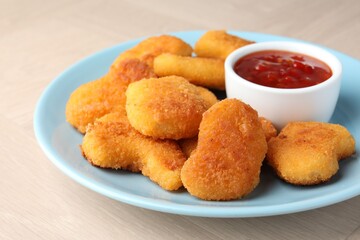 Tasty chicken nuggets with chili sauce on wooden table, closeup