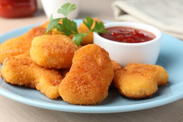 Tasty chicken nuggets with chili sauce and parsley on table, closeup