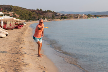 A senior man playing and throwing a Frisbee at the beach
