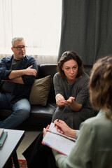 Group of three colleagues discussing strategies during business meeting in office setting with...
