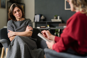 Attentive woman sitting during a counseling session with attentive counselor in a cozy office...