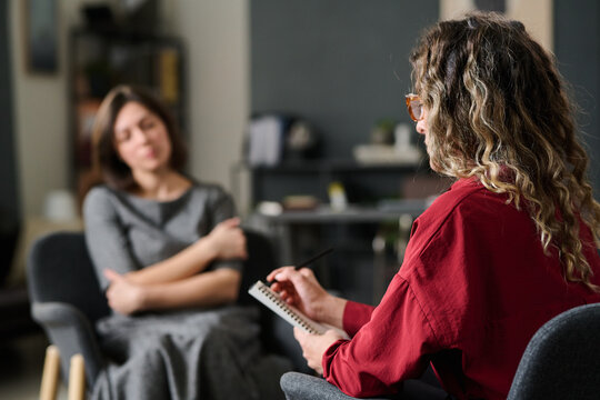 Therapist in red shirt conducting therapy session with a client sitting in office setting with blurred background creating focused atmosphere for evaluation